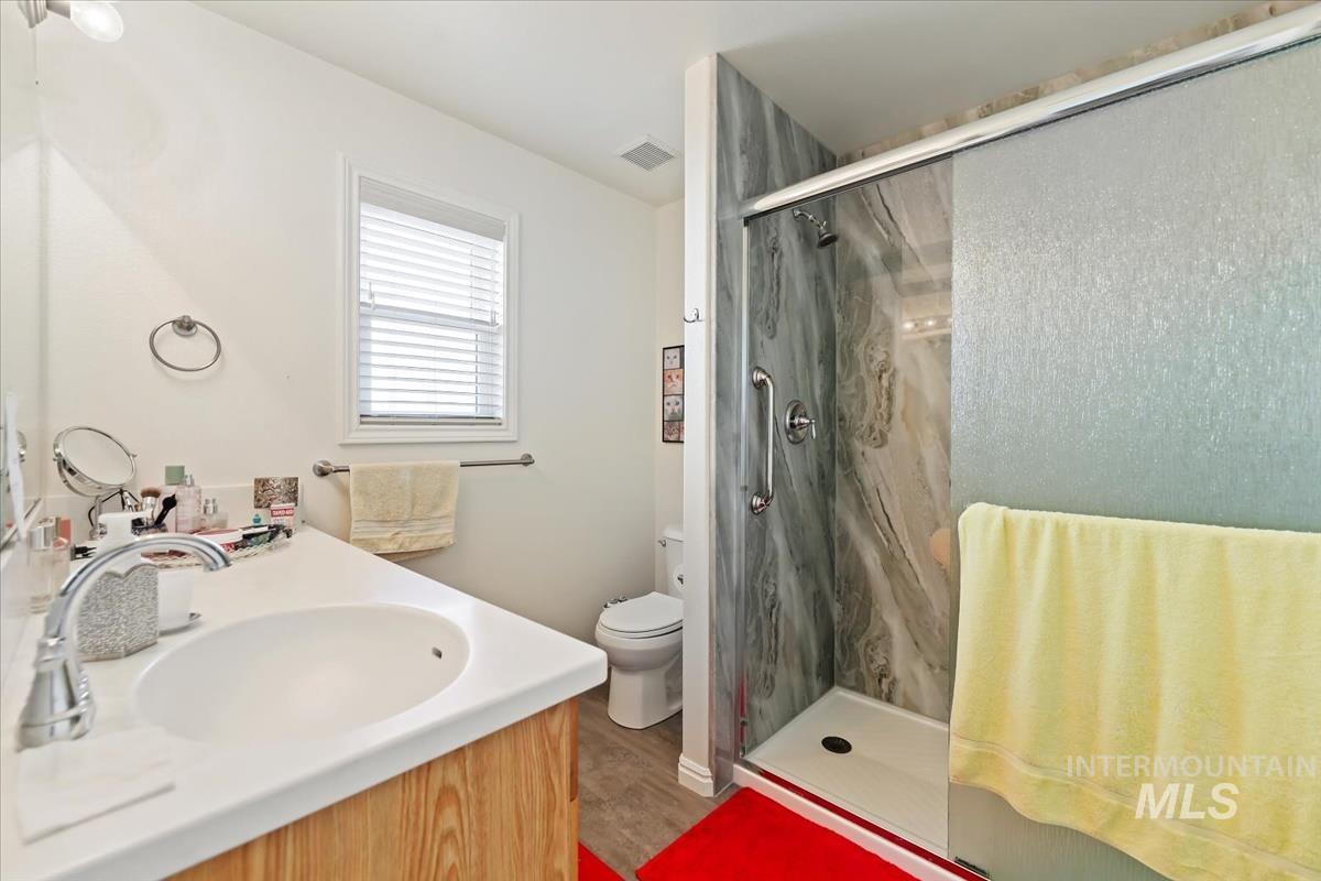 Bathroom with vanity, a marble finish shower, and wood finished floors