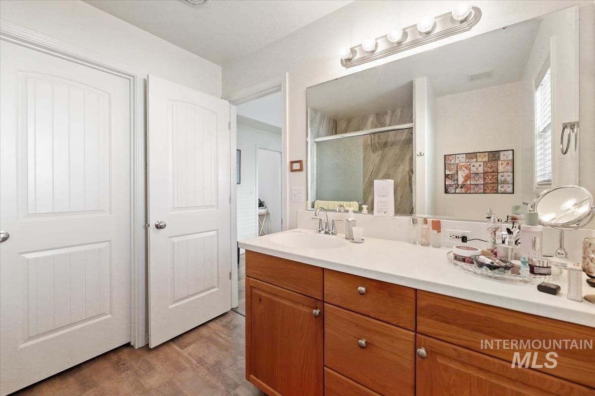 Full bath with vanity, a stall shower, and light wood-style flooring