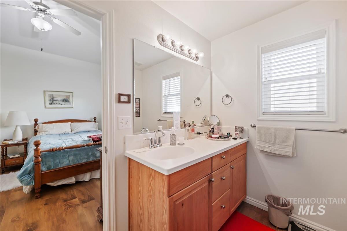 Bathroom featuring vanity, dark wood-type flooring, ensuite bath, and ceiling fan