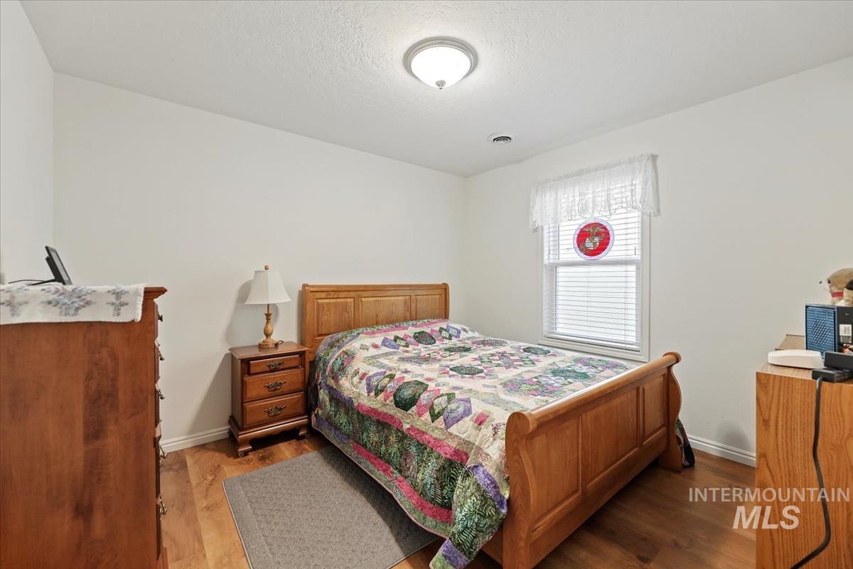 Bedroom with wood finished floors and a textured ceiling