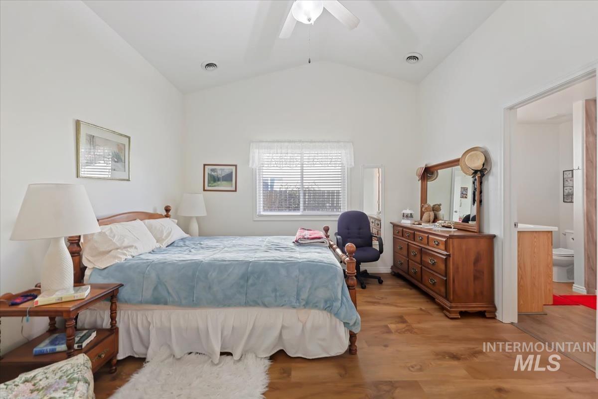 Bedroom with wood finished floors, lofted ceiling, and a ceiling fan