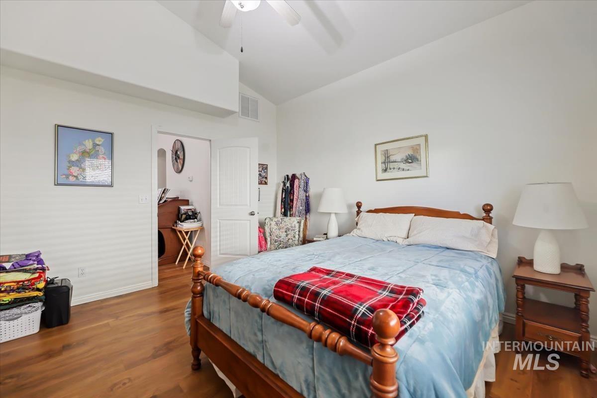 Bedroom featuring dark wood-style floors, lofted ceiling, and ceiling fan