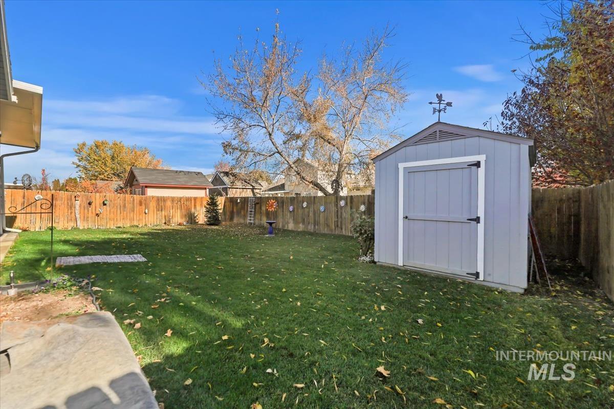 Fenced backyard featuring a storage shed
