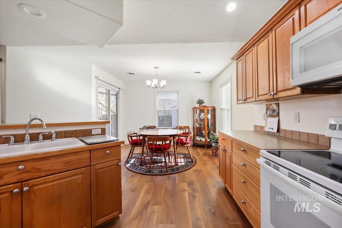 Kitchen with white appliances, light wood-style flooring, decorative light fixtures, plenty of natural light, and recessed lighting