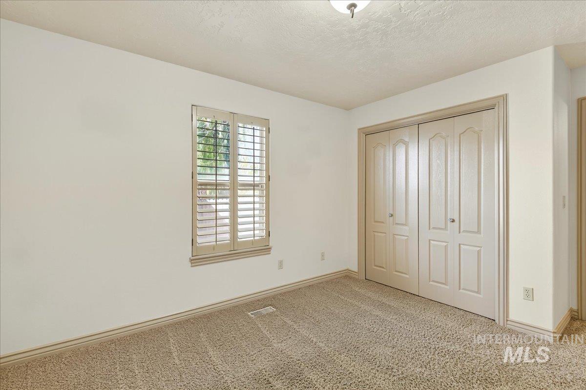 Unfurnished bedroom featuring a textured ceiling, light carpet, and a closet