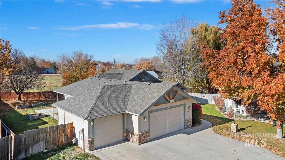 View of front of house featuring a shingled roof, stone siding, and a garage