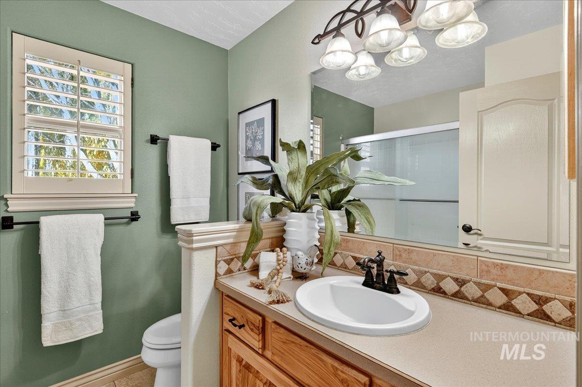 Full bathroom with vanity, a stall shower, tasteful backsplash, a textured ceiling, and a chandelier