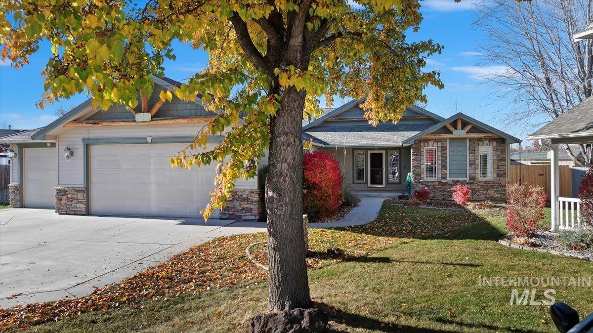 View of front of house with stone siding, a front lawn, a garage, concrete driveway, and a porch