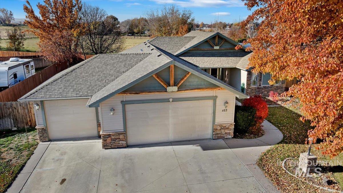 View of front of property with stone siding, a shingled roof, driveway, and an attached garage