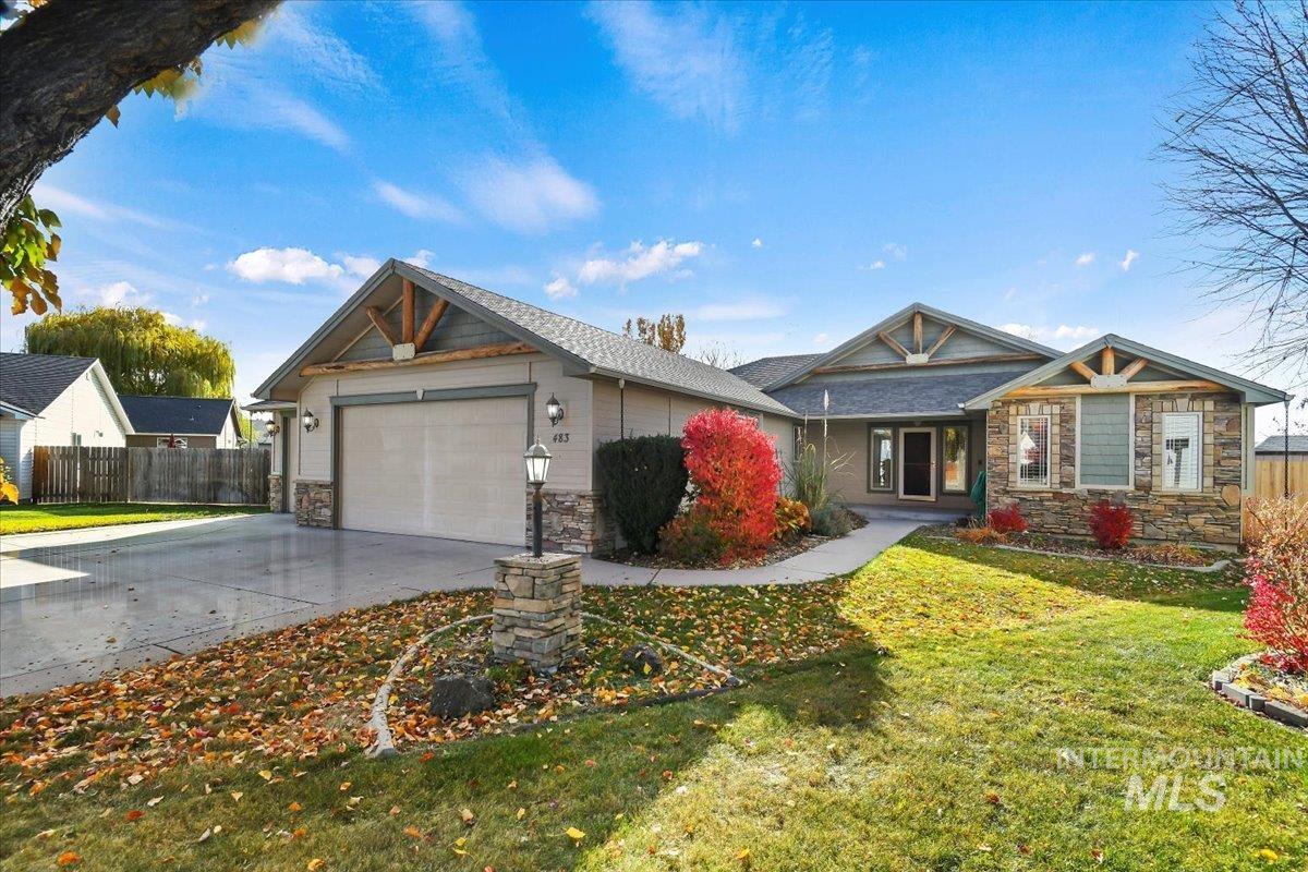 View of front facade featuring stone siding, concrete driveway, a garage, and covered porch