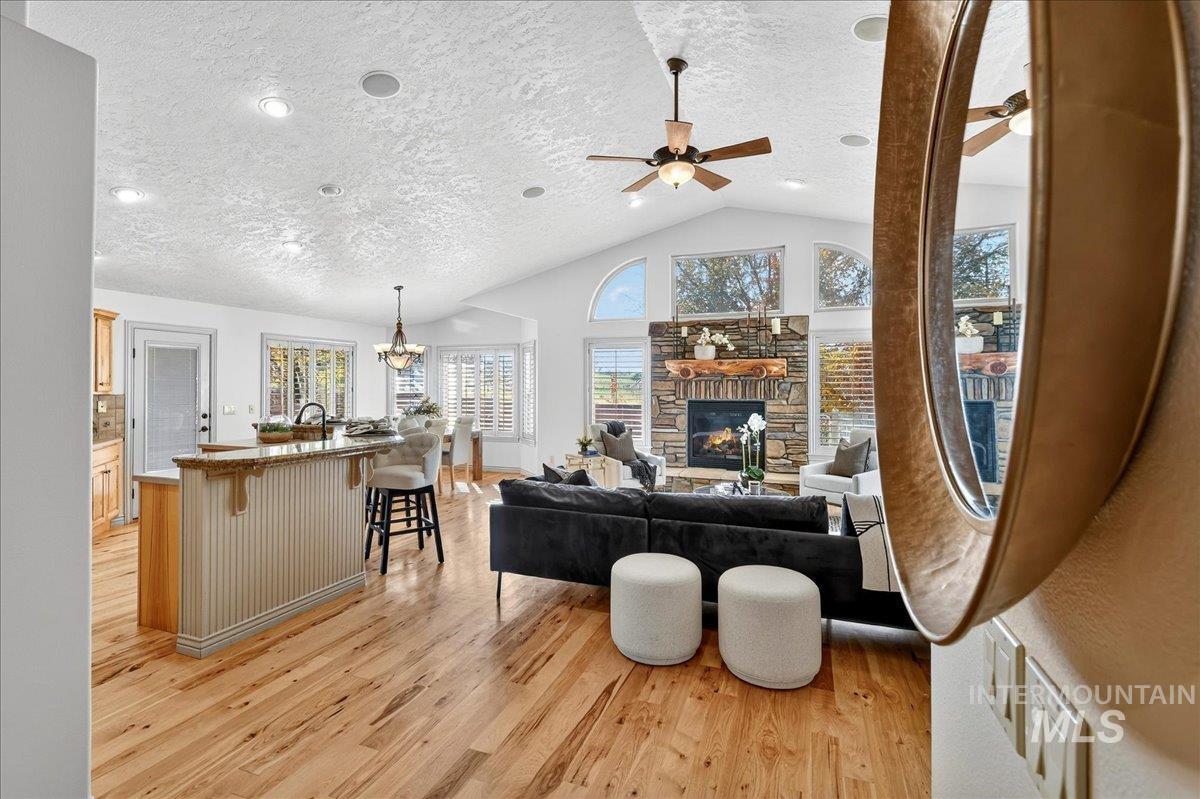 Living room with light wood finished floors, a textured ceiling, a fireplace, a chandelier, and high vaulted ceiling
