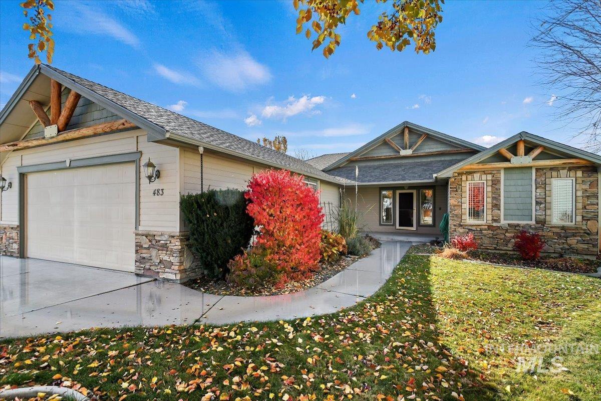 Craftsman-style house with stone siding, covered porch, an attached garage, and a front yard