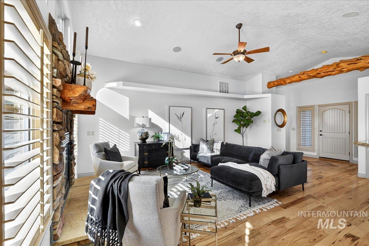 Living area with lofted ceiling, light wood-style floors, a textured ceiling, and a ceiling fan