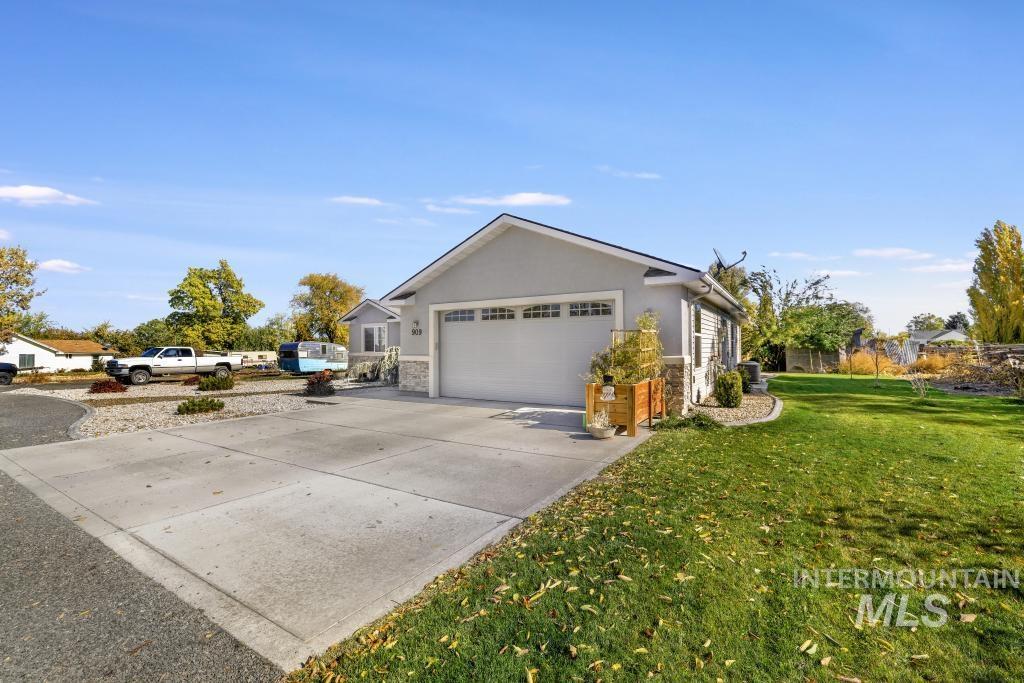 View of side of property with stucco siding, concrete driveway, stone siding, a lawn, and a garage