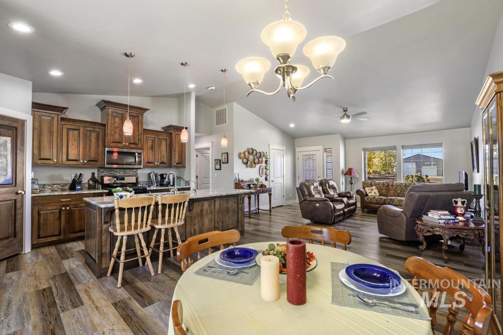 Dining space with dark wood-style flooring, a chandelier, a ceiling fan, recessed lighting, and high vaulted ceiling