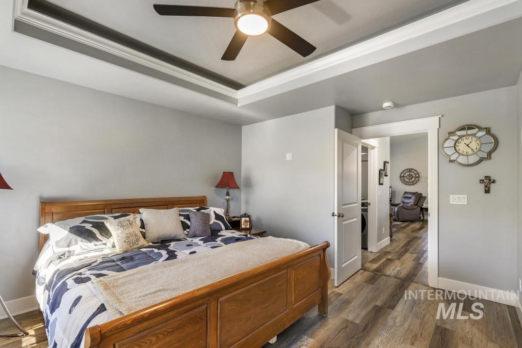 Bedroom featuring dark wood-type flooring, ceiling fan, and a tray ceiling