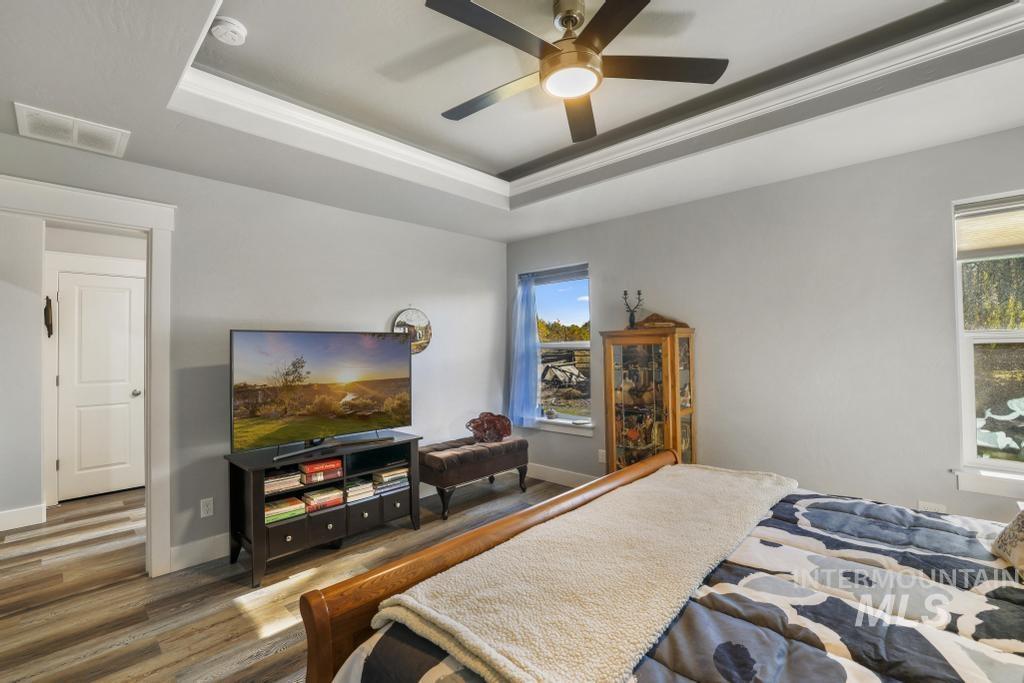 Bedroom featuring a tray ceiling, wood finished floors, and ceiling fan
