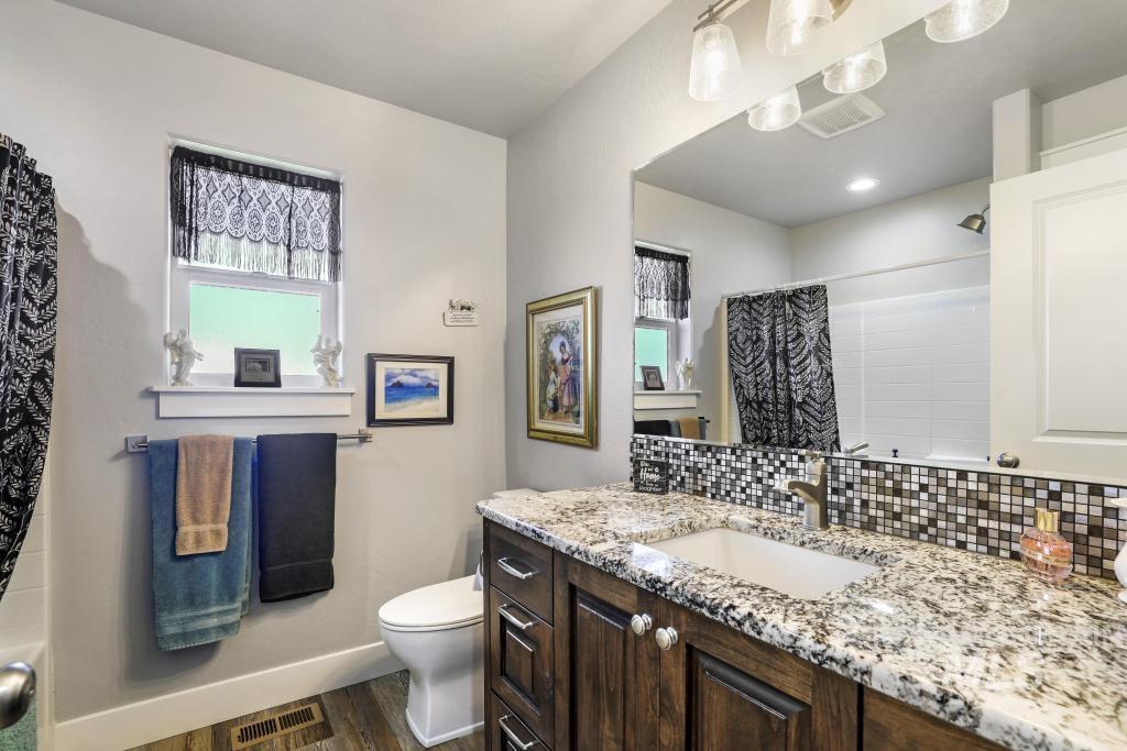Full bath with vanity, a shower with curtain, dark wood-style floors, backsplash, and plenty of natural light