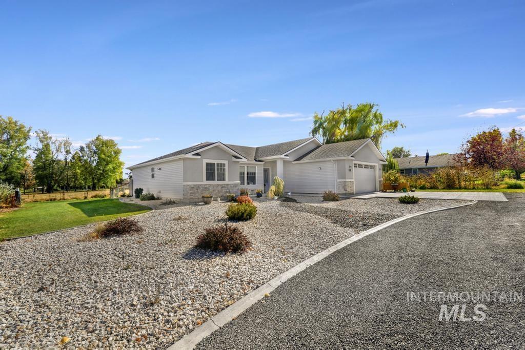 Ranch-style home featuring stone siding, an attached garage, driveway, and a front lawn