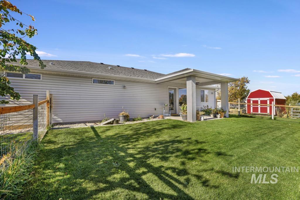 Rear view of property featuring a patio area, a shed, and a shingled roof