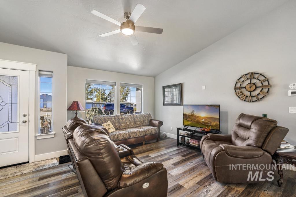 Living room with lofted ceiling, dark wood finished floors, and a ceiling fan