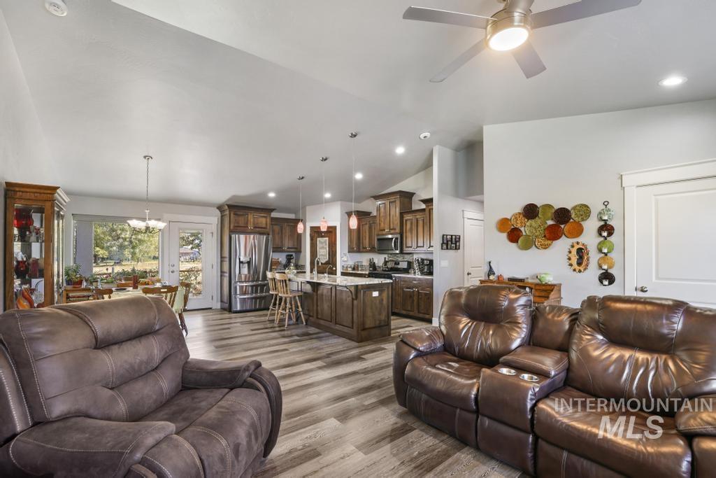 Living room with lofted ceiling, recessed lighting, light wood-style flooring, a chandelier, and ceiling fan