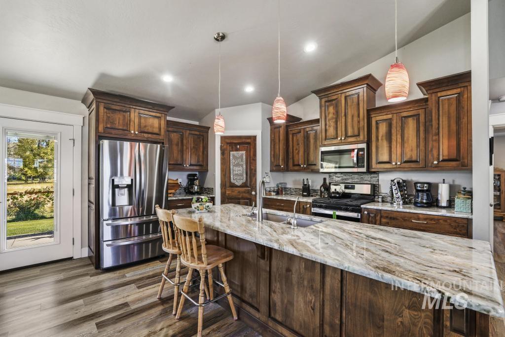 Kitchen with dark brown cabinetry, appliances with stainless steel finishes, pendant lighting, dark wood finished floors, and recessed lighting
