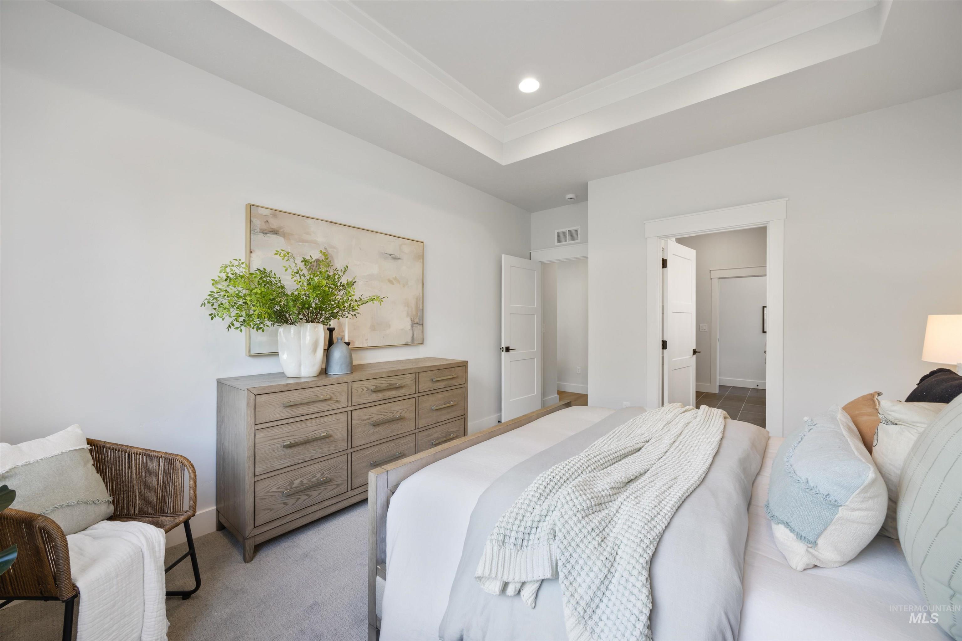 Carpeted bedroom featuring a tray ceiling, crown molding, recessed lighting, and connected bathroom