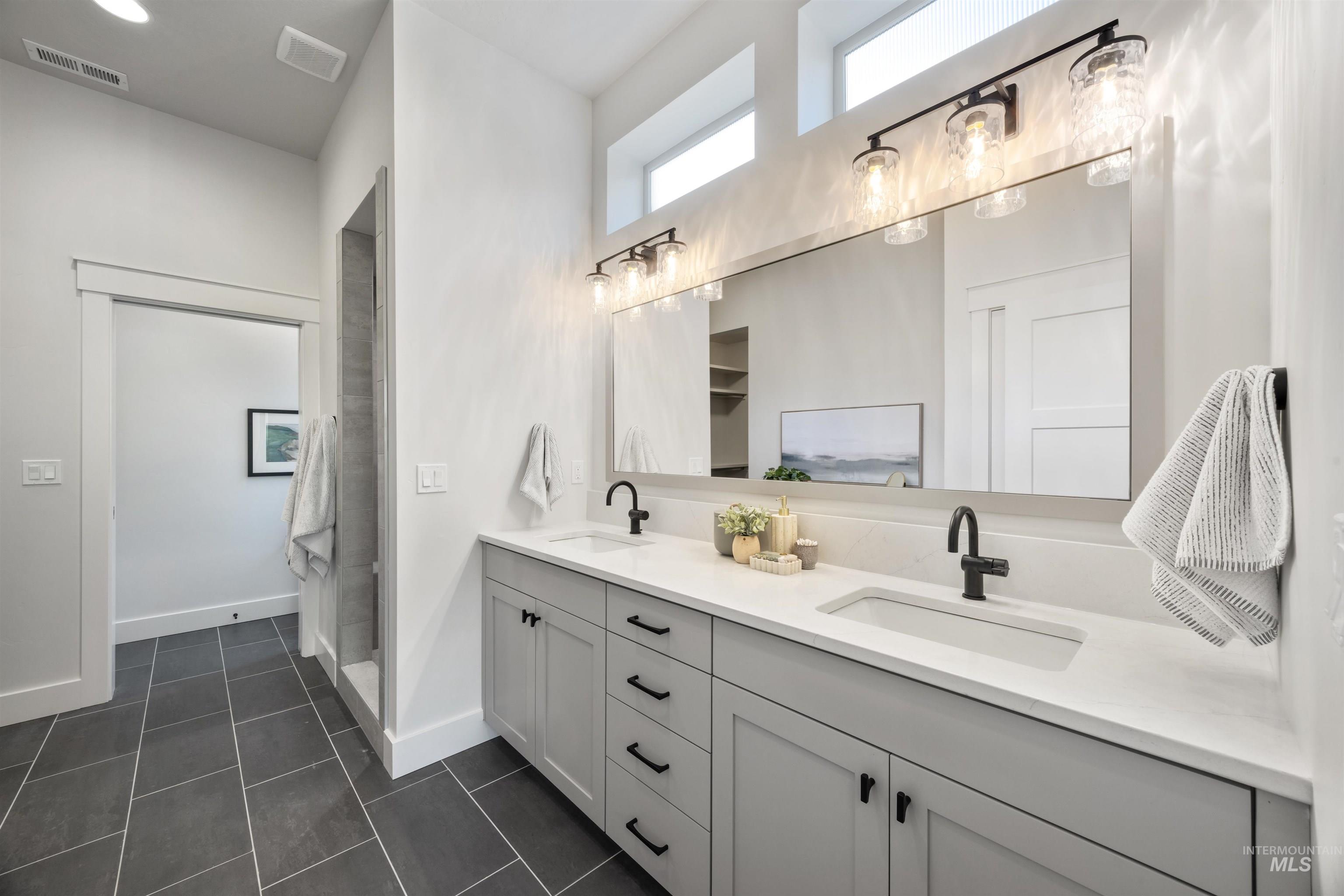 Bathroom with double vanity and dark tile patterned flooring