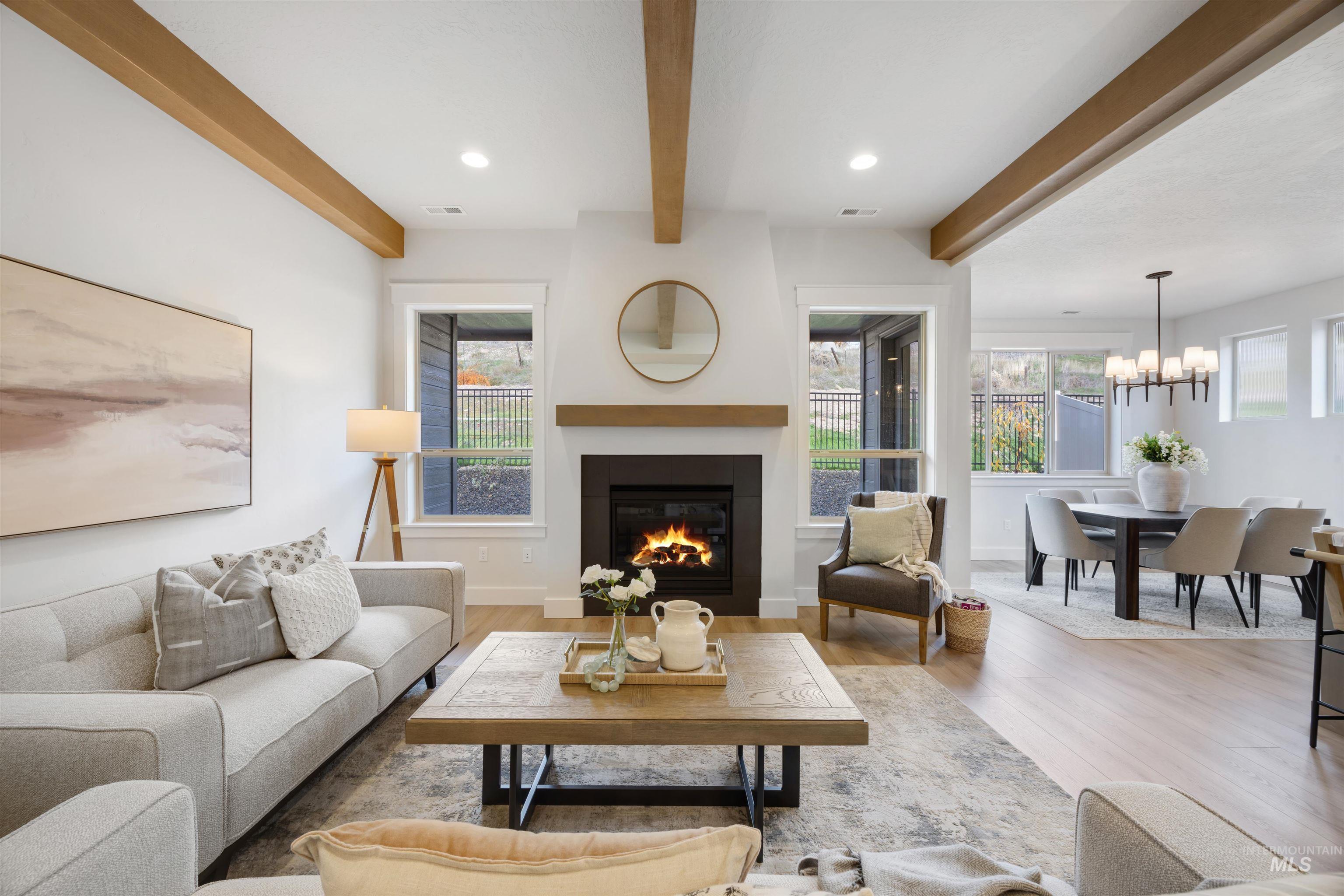 Living area featuring a glass covered fireplace, beam ceiling, wood finished floors, recessed lighting, and a chandelier