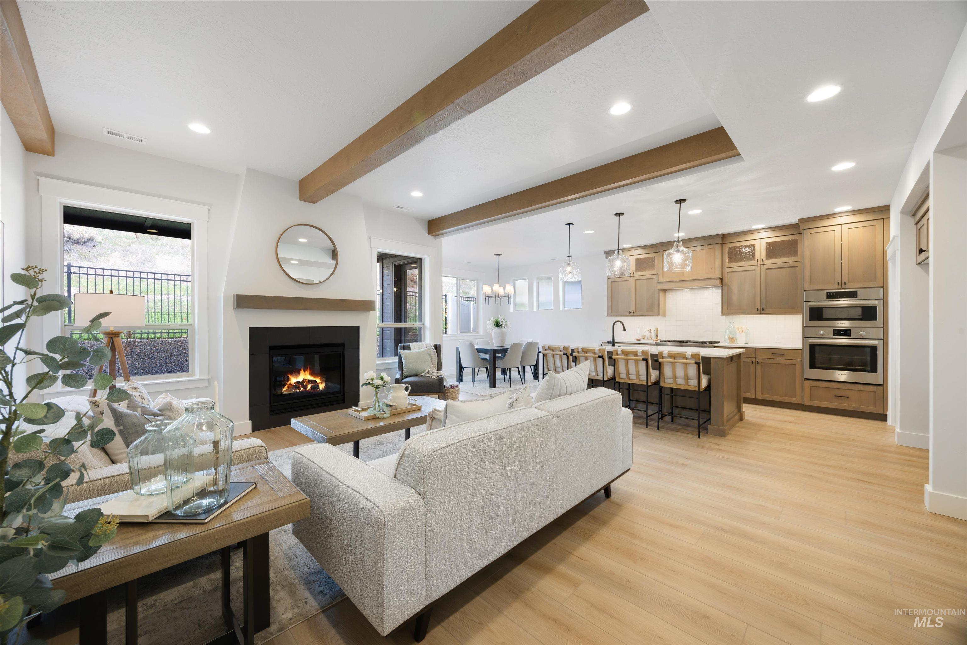Living area featuring beamed ceiling, healthy amount of natural light, recessed lighting, light wood finished floors, and a chandelier