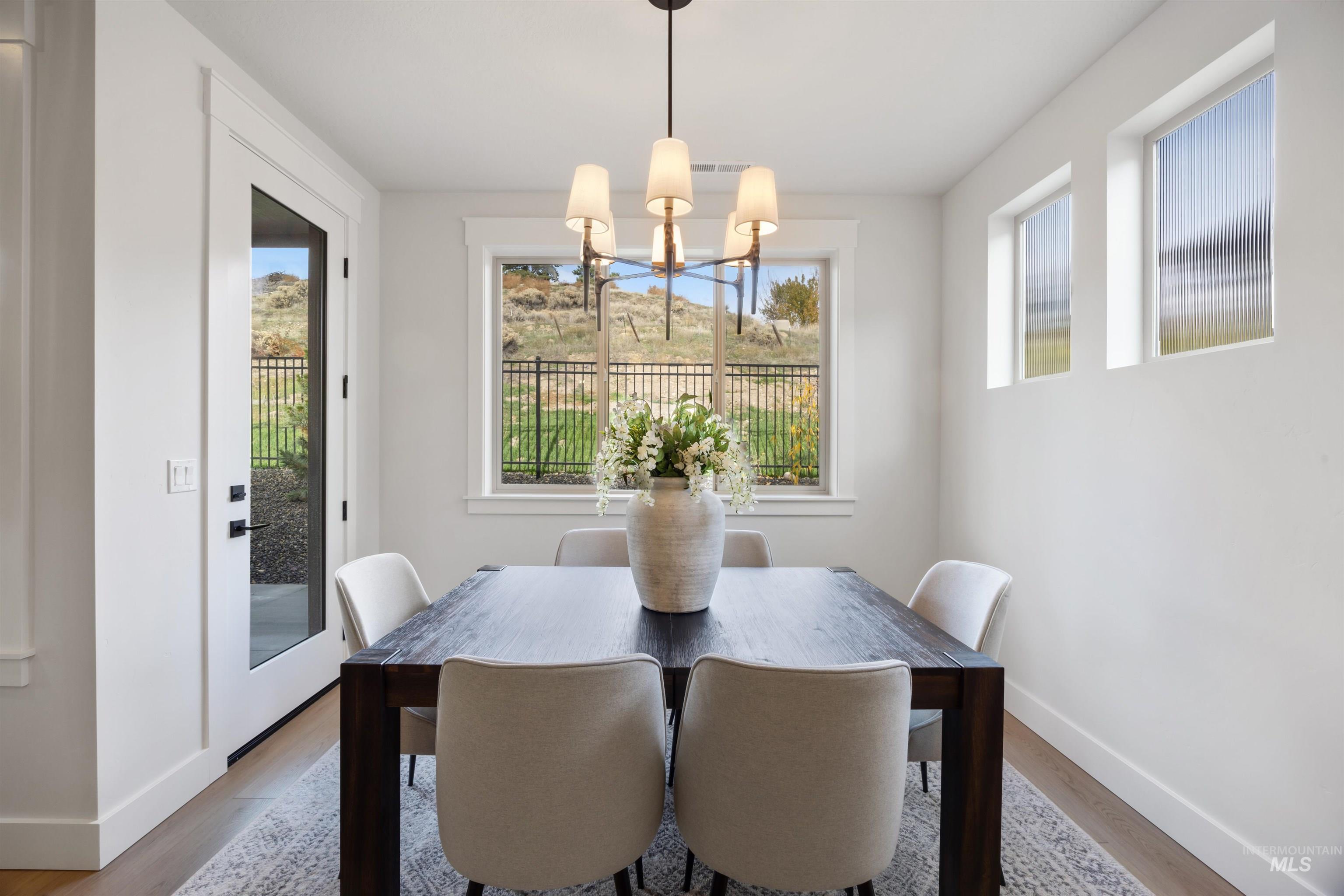 Dining space with wood finished floors, healthy amount of natural light, and a chandelier