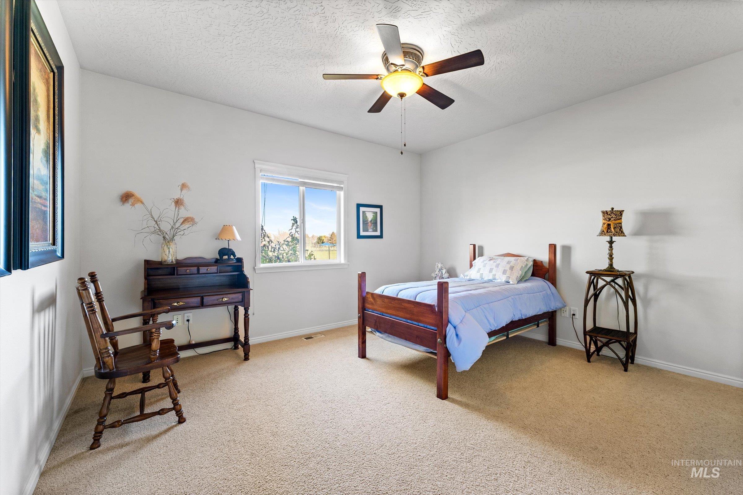Bedroom featuring light colored carpet, a textured ceiling, and ceiling fan