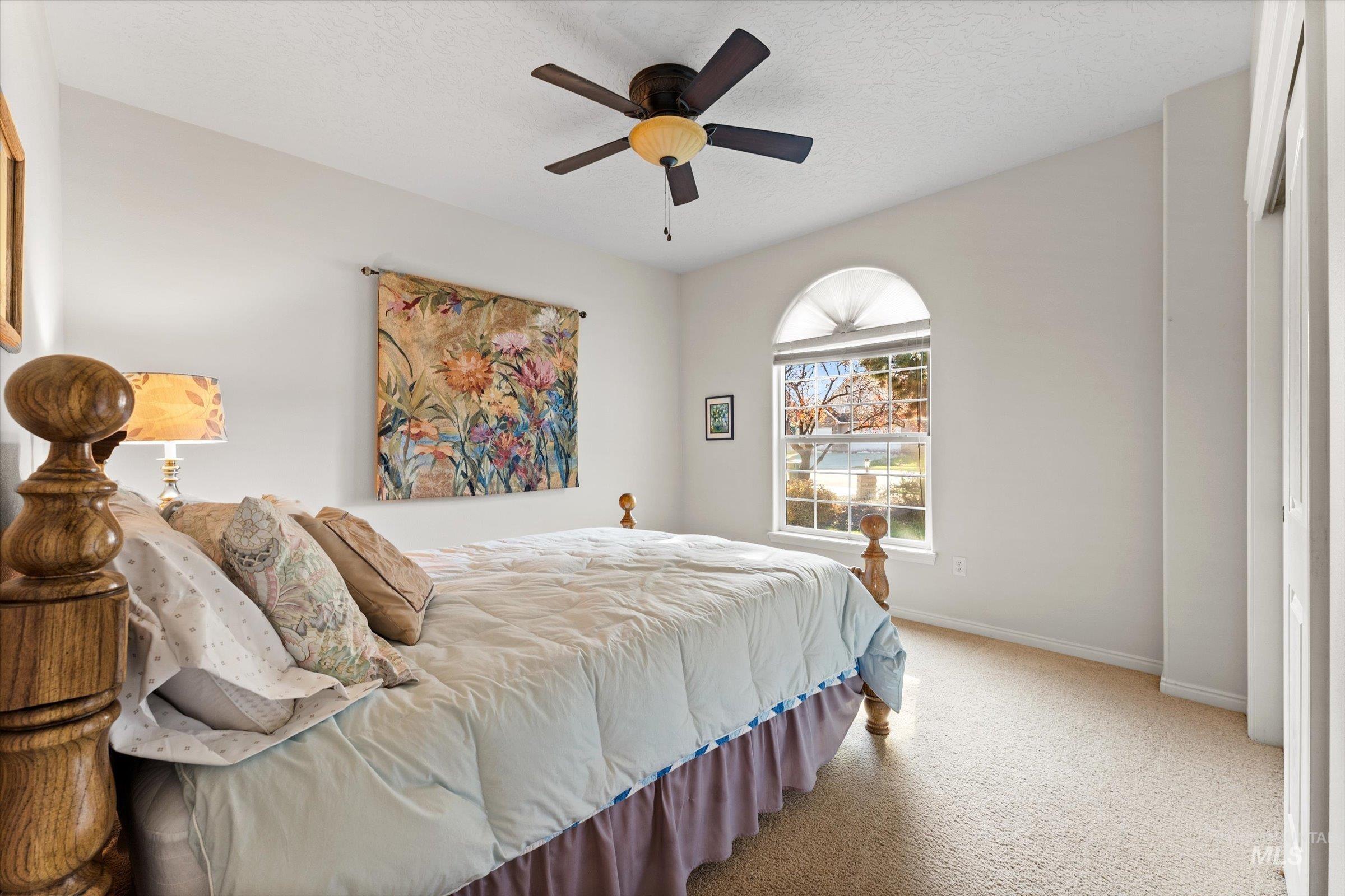 Bedroom with carpet floors, a ceiling fan, and a textured ceiling