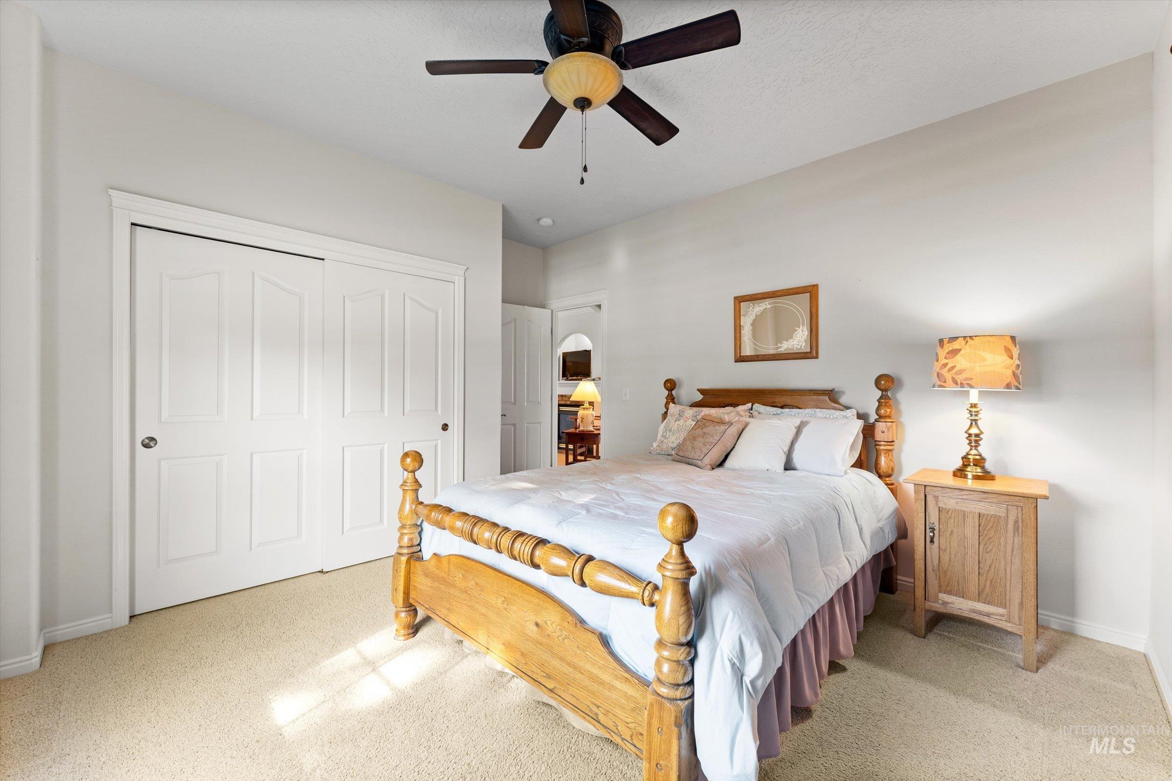 Bedroom with light colored carpet, a closet, a ceiling fan, and arched walkways