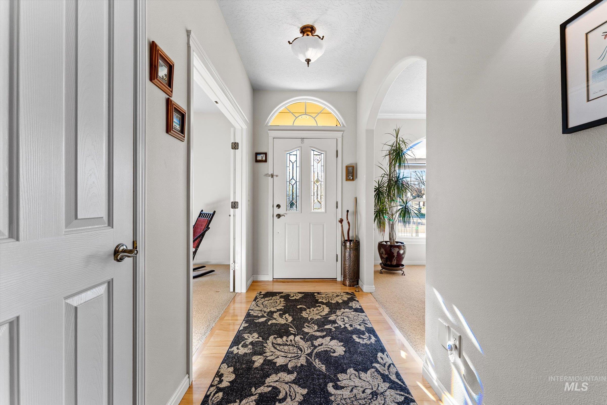 Entryway with light wood-style floors, arched walkways, and a textured ceiling