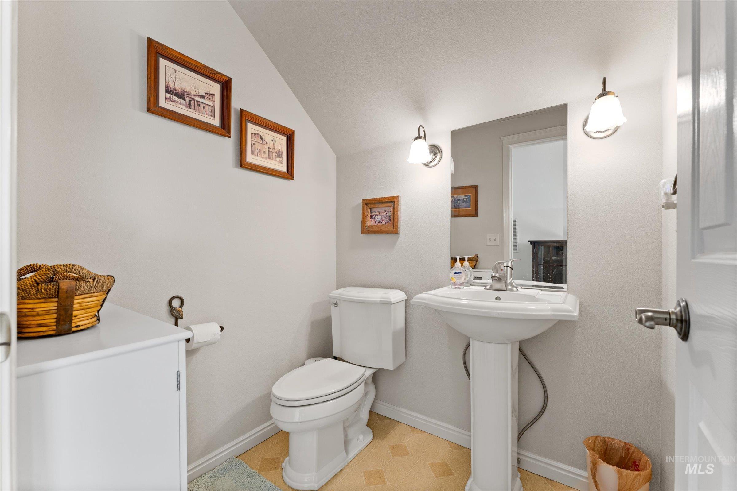 Half bathroom with toilet and lofted ceiling