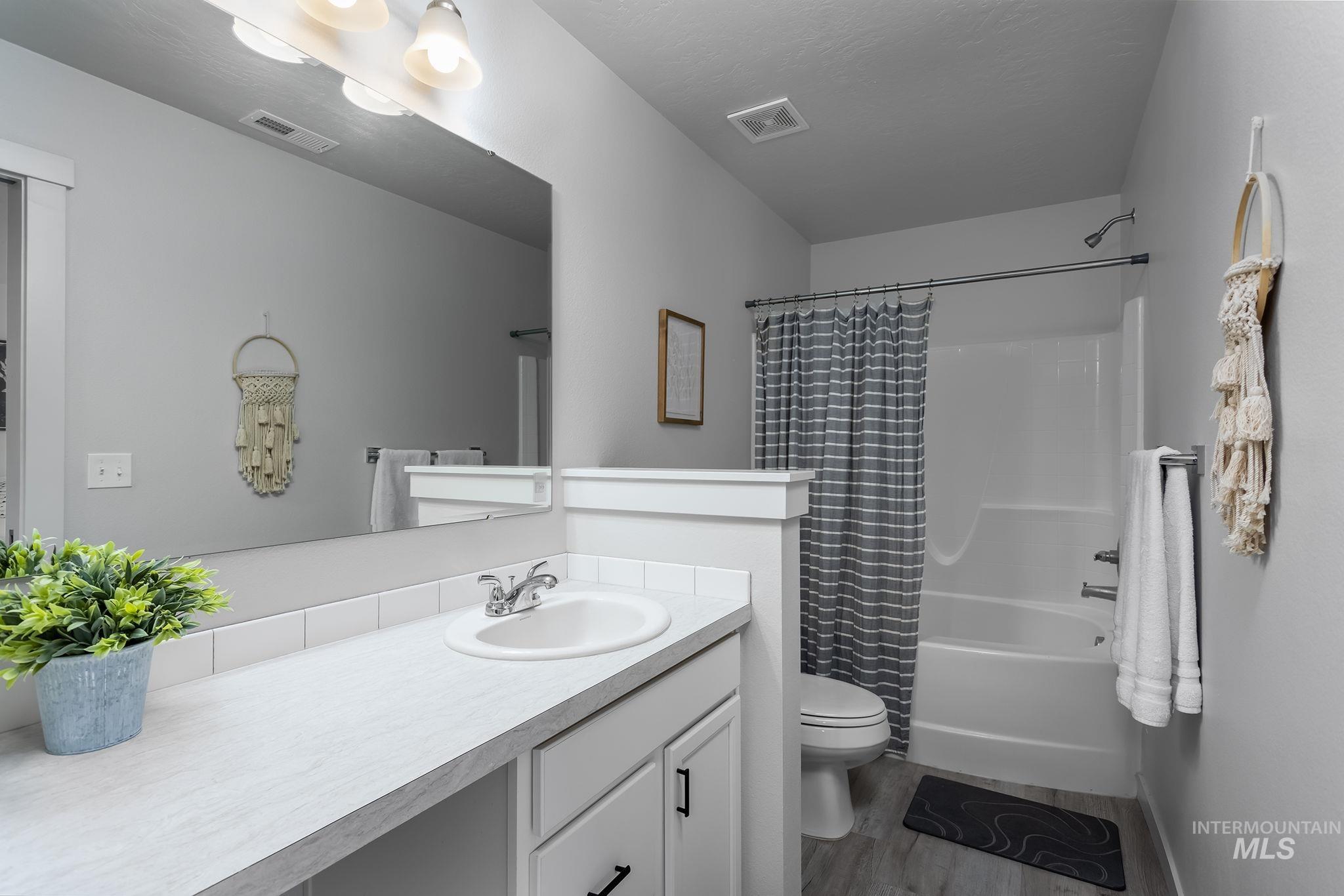 Full bathroom featuring vanity, shower / bath combo with shower curtain, and dark wood-type flooring