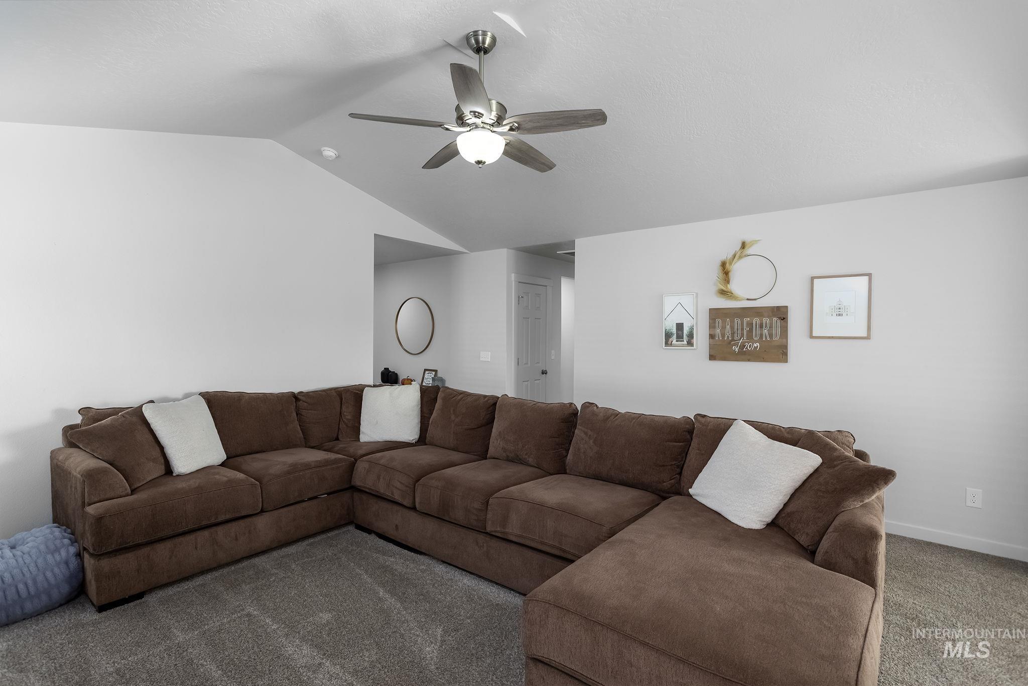 Carpeted living area with vaulted ceiling and a ceiling fan