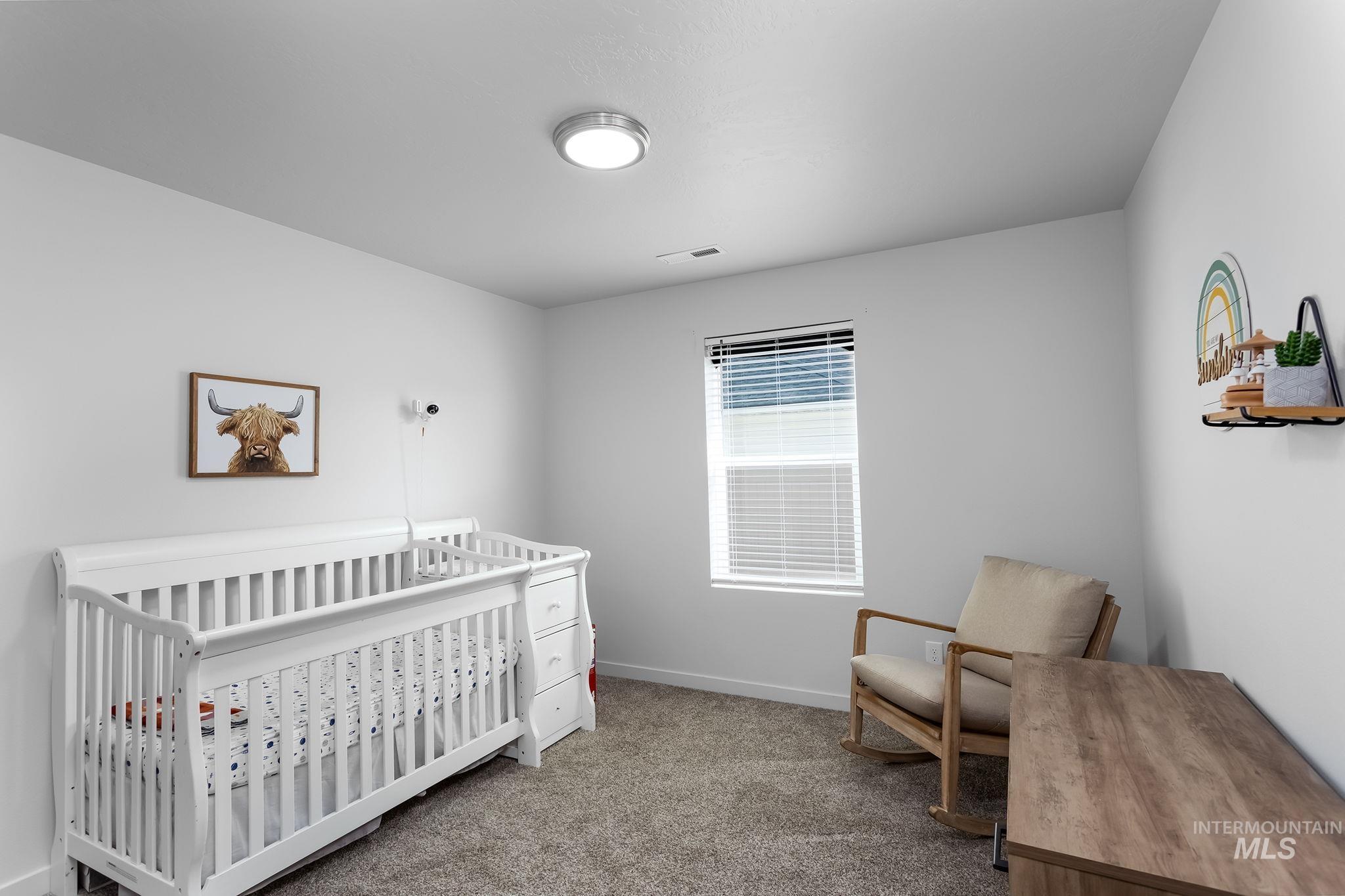 Bedroom featuring light colored carpet and a nursery area