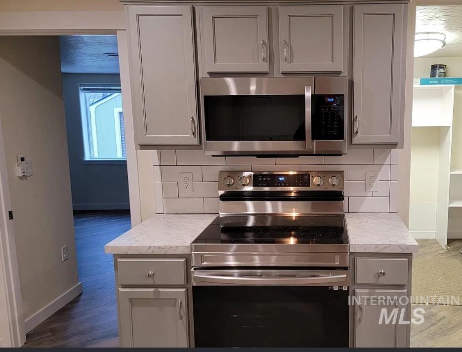 Kitchen featuring appliances with stainless steel finishes, decorative backsplash, gray cabinets, and light countertops