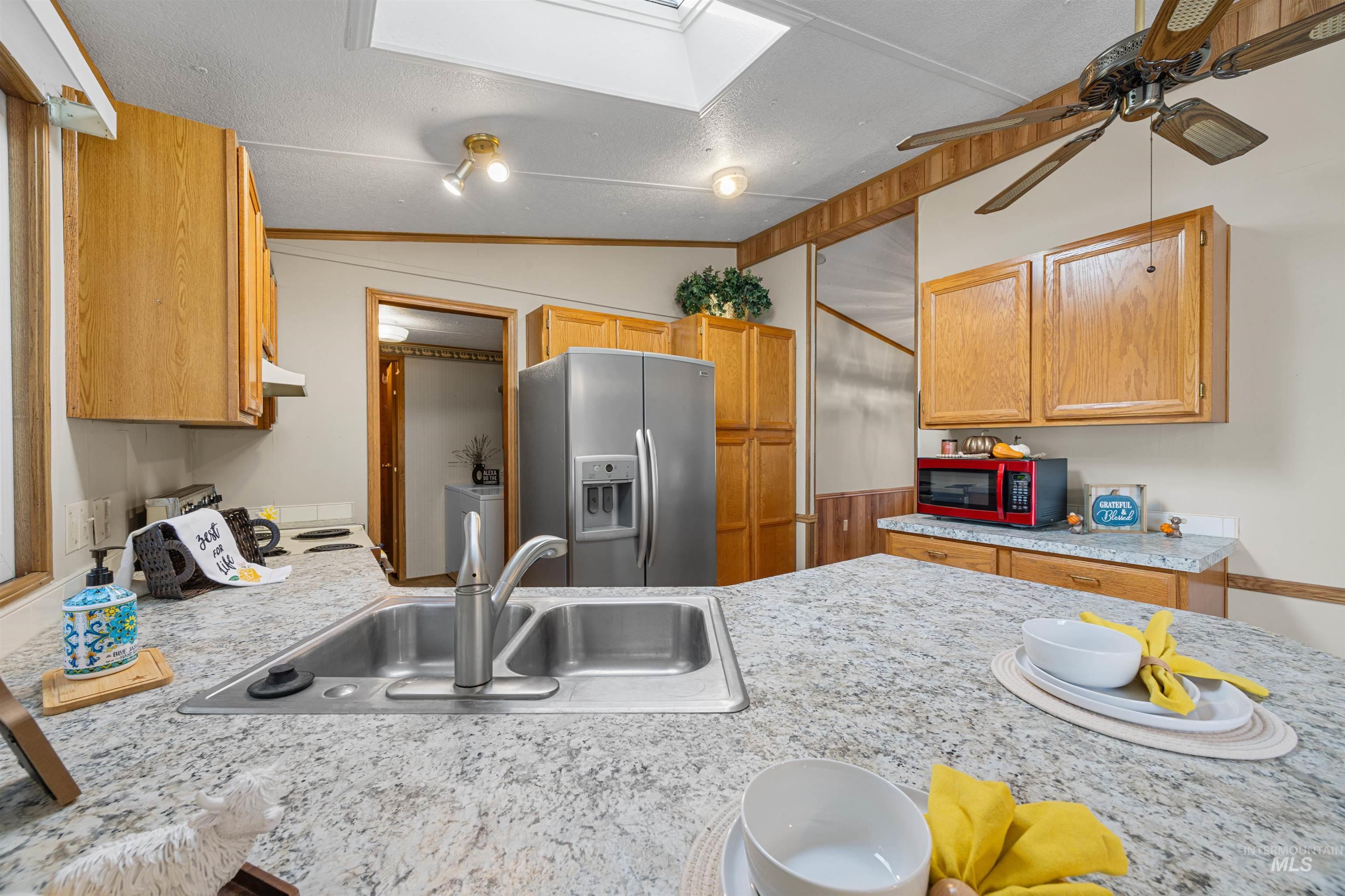 Kitchen featuring light countertops, stainless steel refrigerator with ice dispenser, lofted ceiling, range with electric cooktop, and ceiling fan