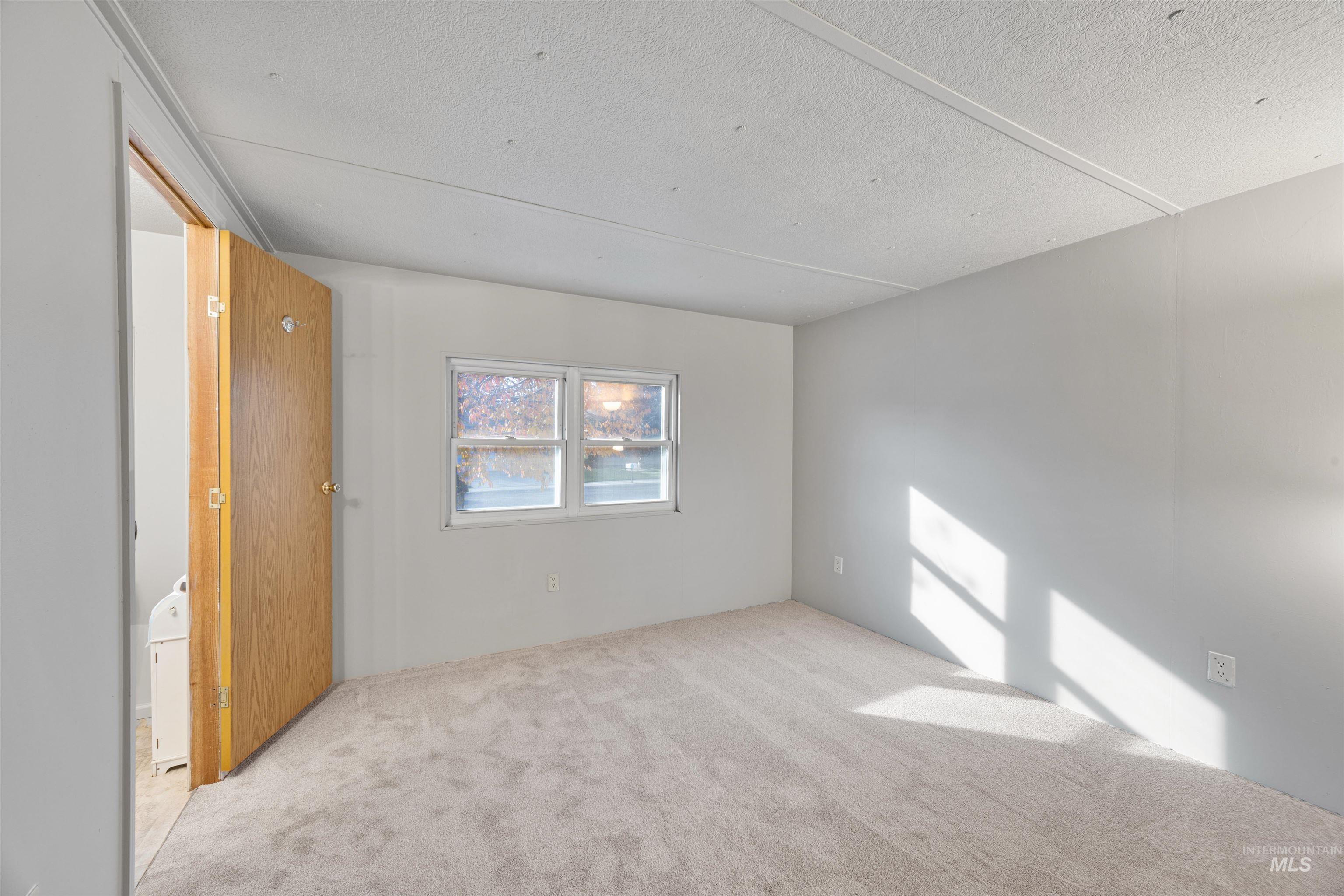 Bedroom two with en-suite bath featuring carpet floors and a textured ceiling