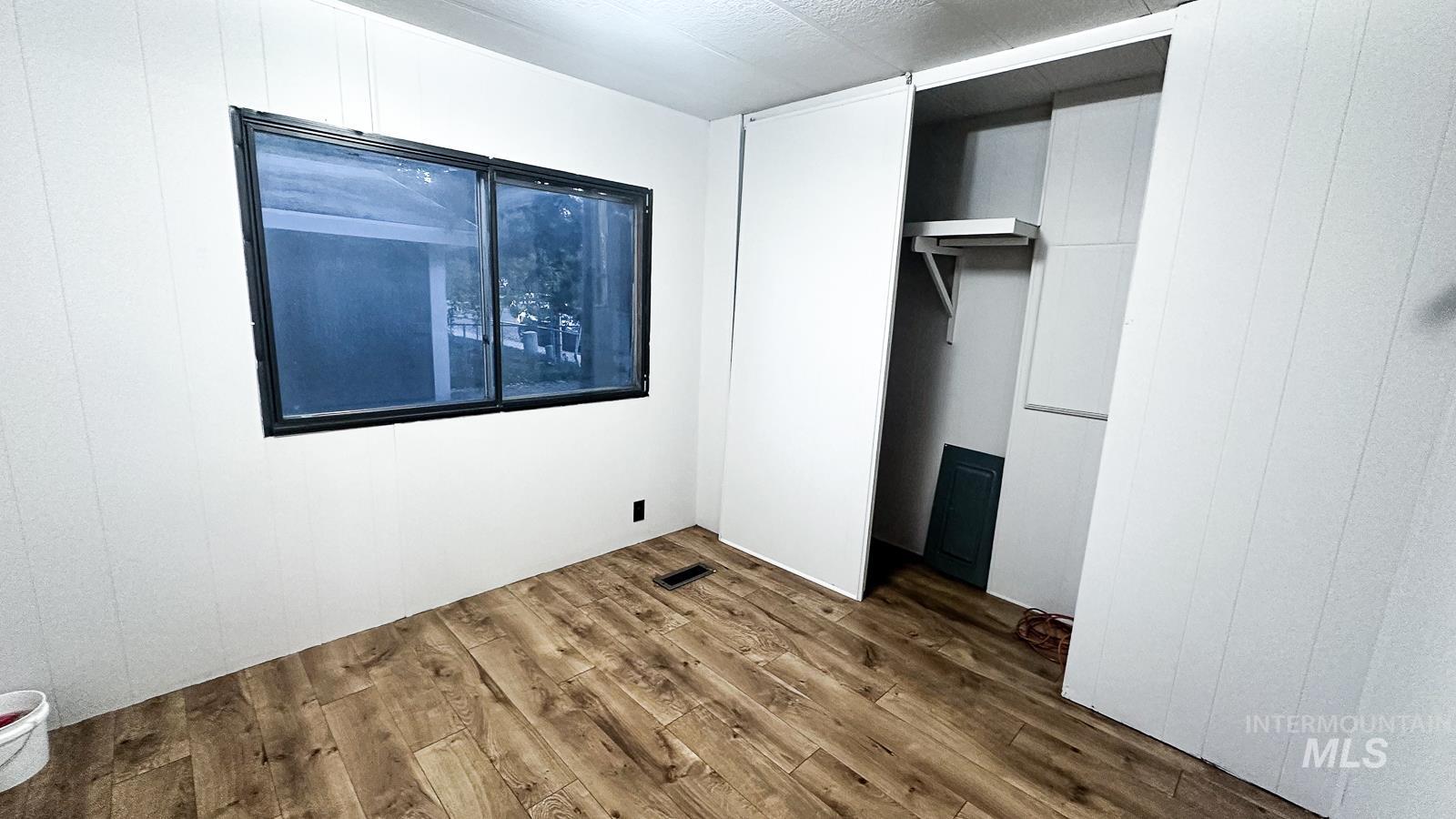 Unfurnished bedroom with wood finished floors and a closet
