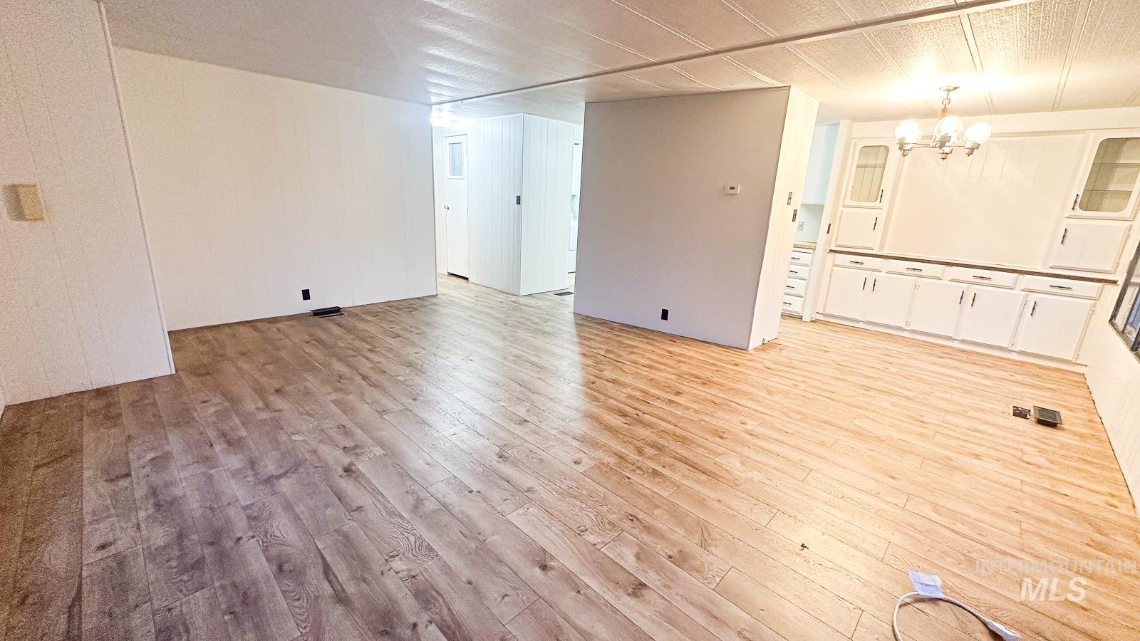 Unfurnished room featuring light wood-type flooring and a chandelier