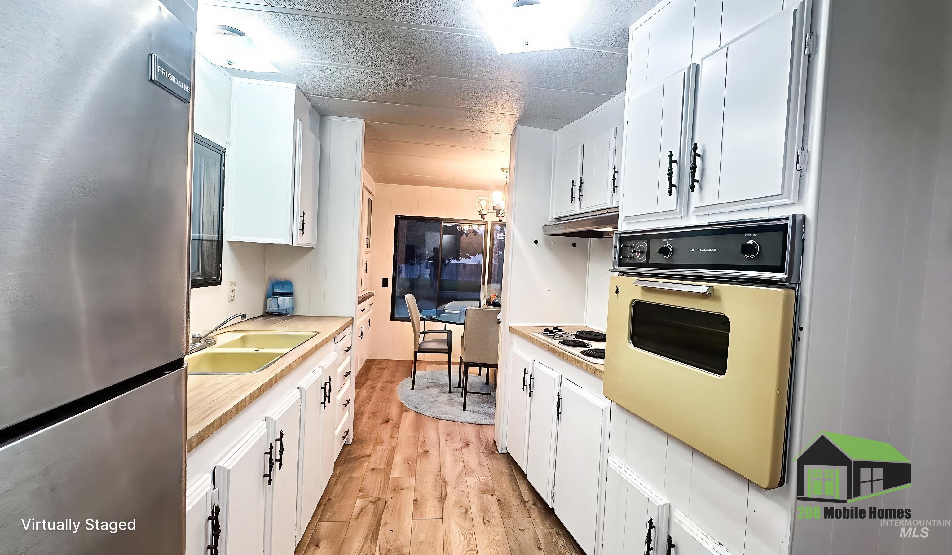Kitchen with freestanding refrigerator, white cabinetry, a chandelier, and light wood-type flooring
