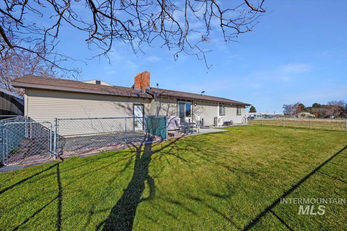 Rear view of house featuring a fenced backyard, a patio area, and a chimney