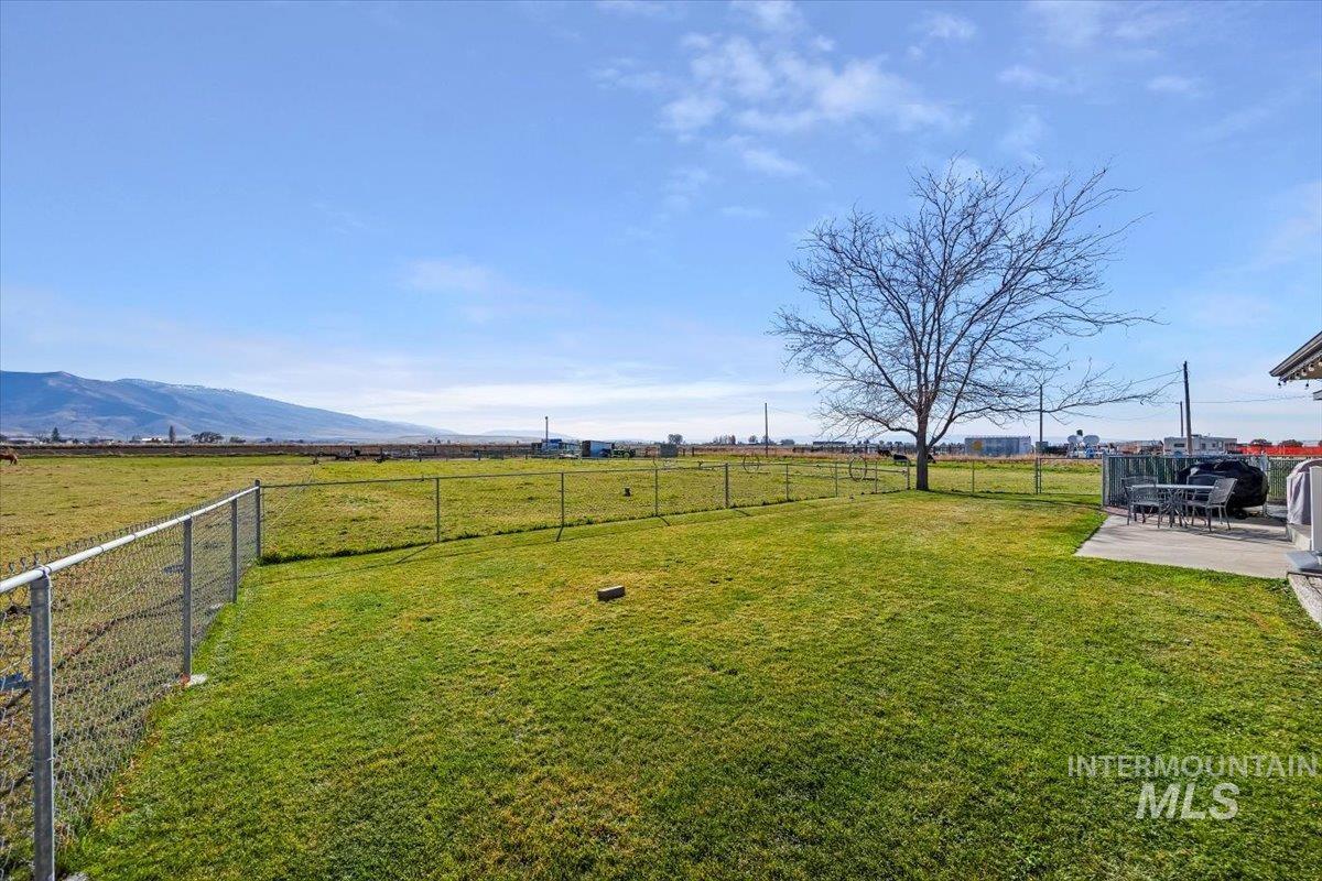 Fenced backyard with a view of countryside, a patio, and a mountain view