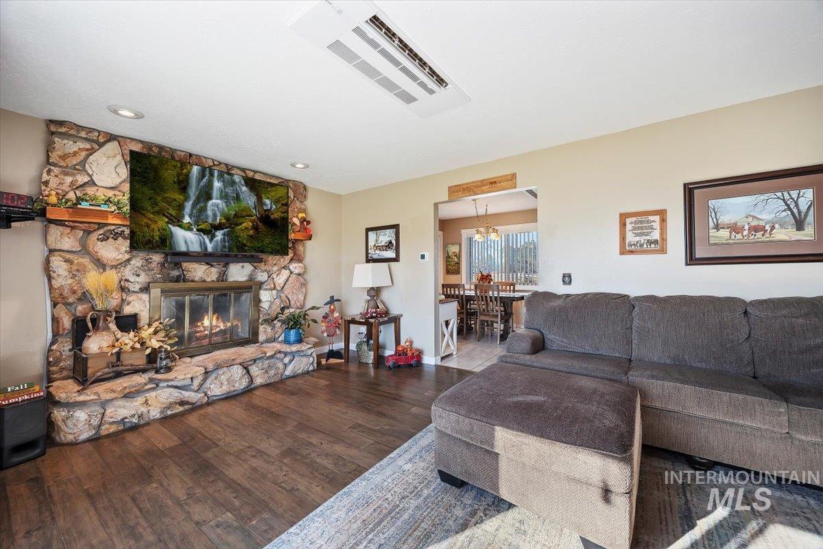 Living room featuring a stone fireplace, wood finished floors, and recessed lighting