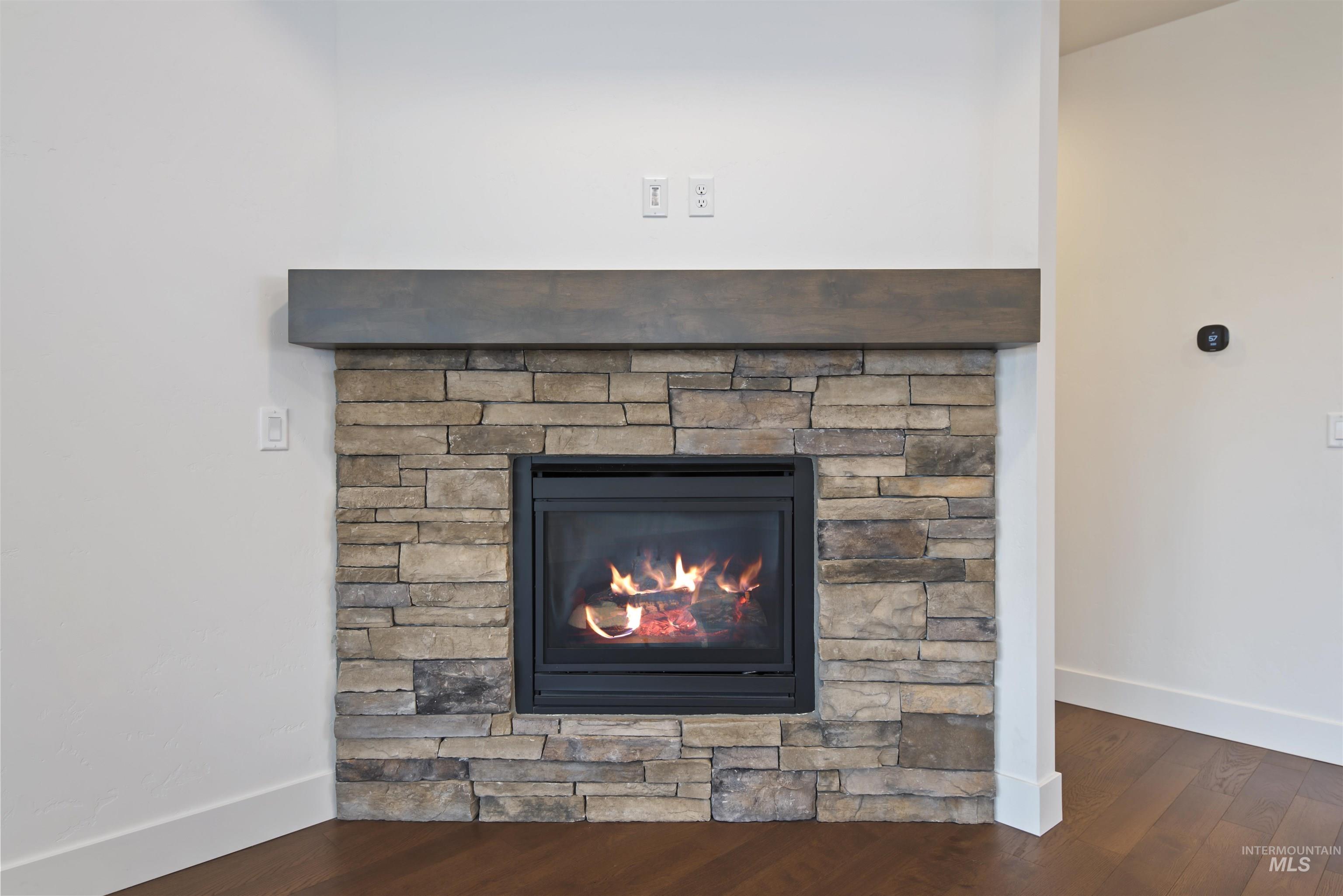 Detailed view of wood finished floors and a stone fireplace